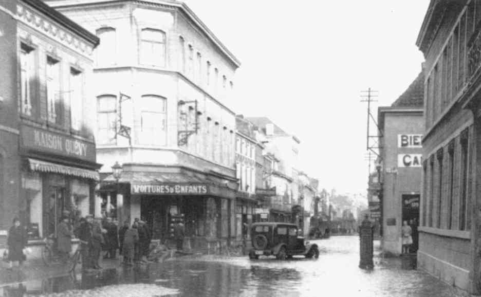 Saint-Ghislain : Le milieu de la Grand-Rue,  gauche, la maison de confection Quvy, spare du bazar Boland par la rue de l' Ecole moyenne. La Grand-Rue est inonde par les dbordements de la Haine.