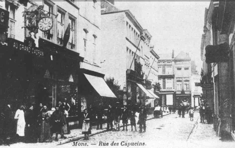 Mons : Rue des Capucins. Nous nous trouvons dans la rue des Capucins. Admirez  gauche la magnifique enseigne de lhorlogerie du Grand Cadran et,  ct, celle bien typique du dbit de tabac de Camille Flament. 